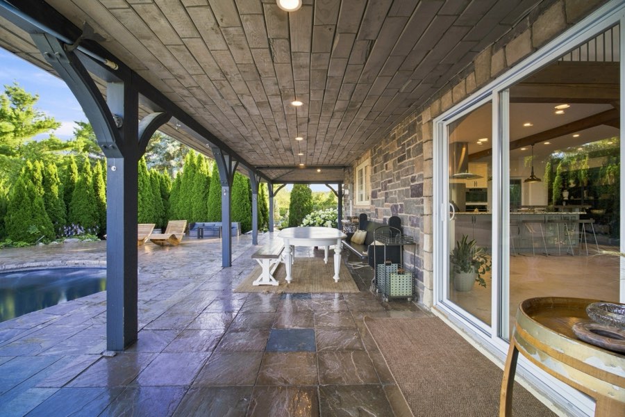 Covered terrace with a dining table, opening through sliding glass into the kitchen