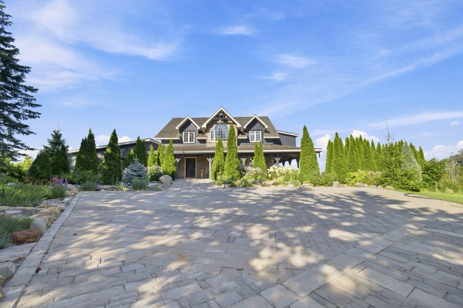 Wide daylight view of the front elevation above a broad stone paver courtyard