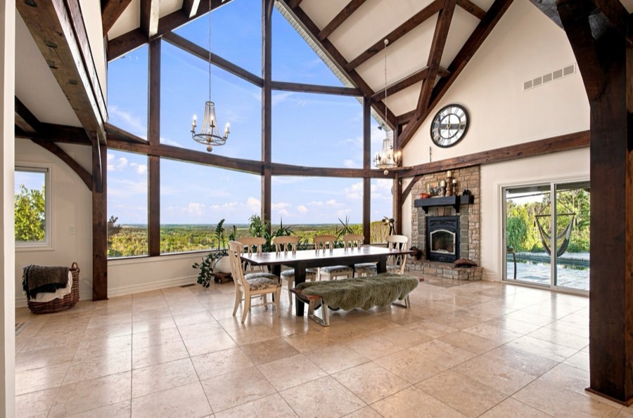 Great room under a two-storey glazed gable, exposed timber trusses overhead and open country beyond