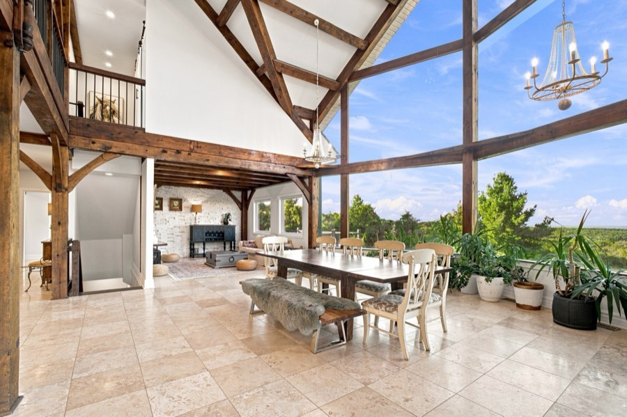 Wide view of the great room showing the timber posts, the open loft above and the wall of glass