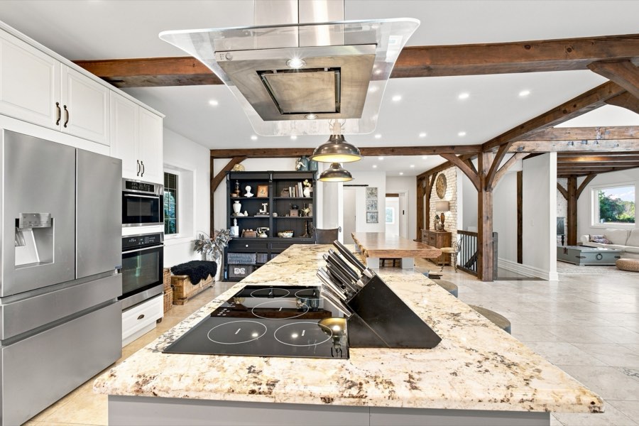 Close view of the granite island cooktop beneath a suspended stainless hood