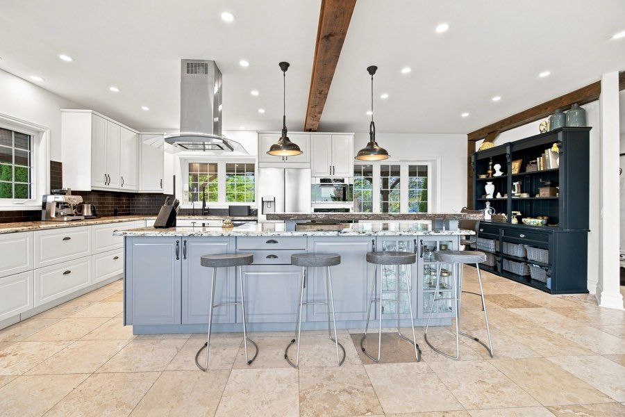 Kitchen with two islands, pale blue cabinetry, pendant lighting and a run of white perimeter units