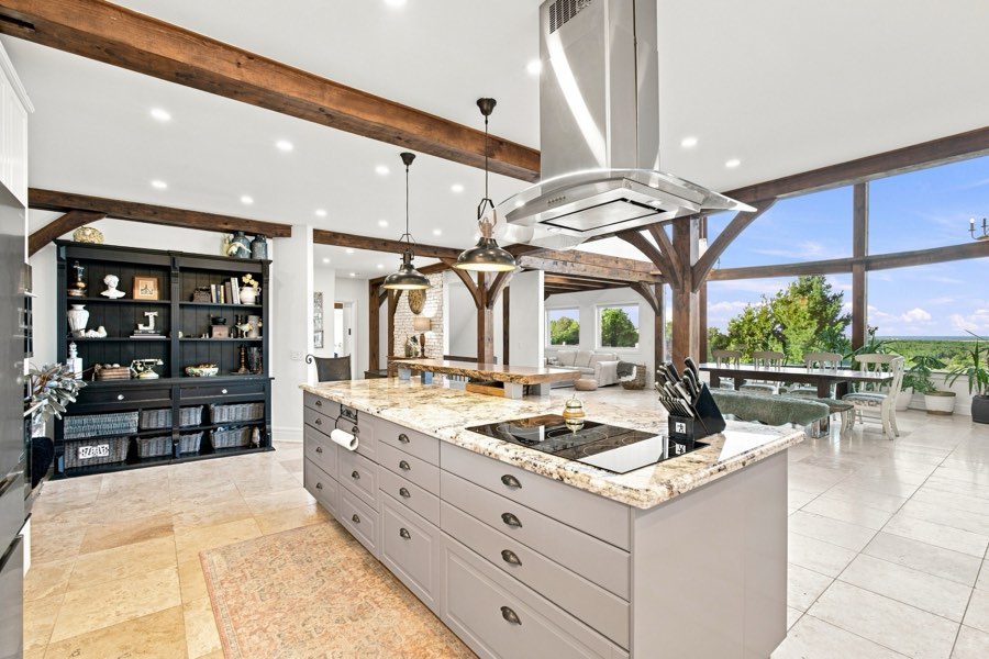 Kitchen with a granite island and stainless hood, opening to the great room and the view beyond