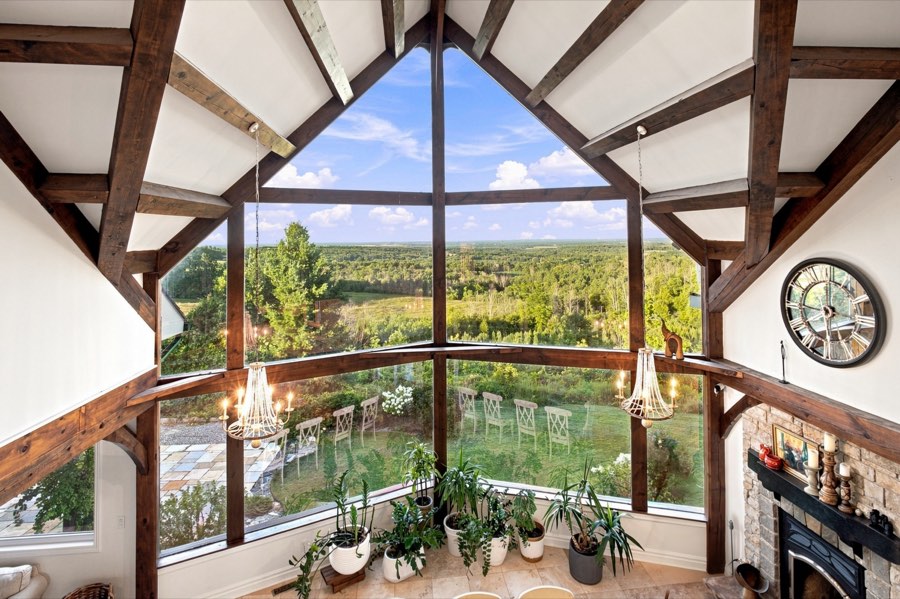 View from the loft down through exposed timber trusses to the cathedral window and fields beyond