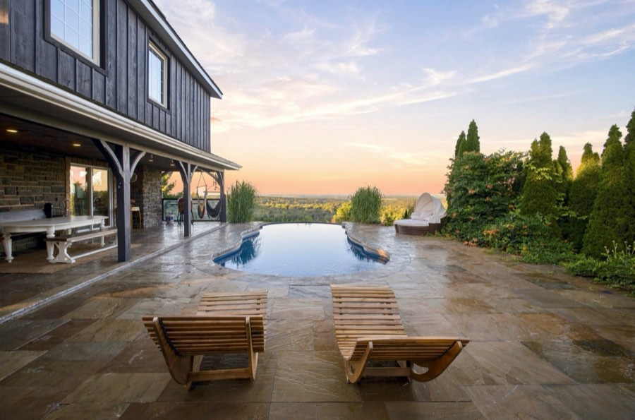 Negative-edge pool and loungers at sunset, the water meeting an open valley beyond