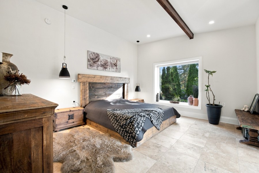 Primary bedroom with a reclaimed timber headboard, pendant bedside lights and a garden window