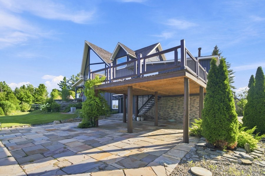 Raised timber deck above a flagstone terrace, with lawn running to the tree line